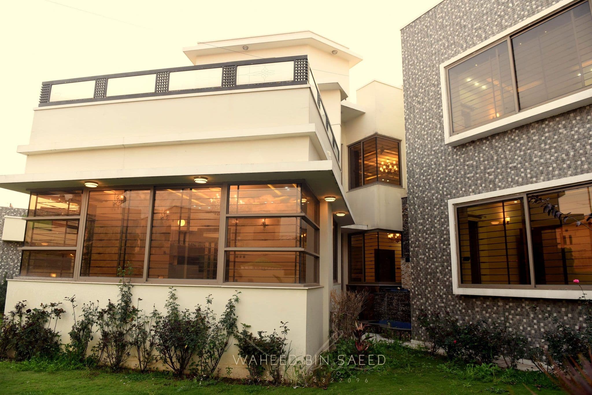 A cream home with warmly lit windows and a mosaic-tile wing